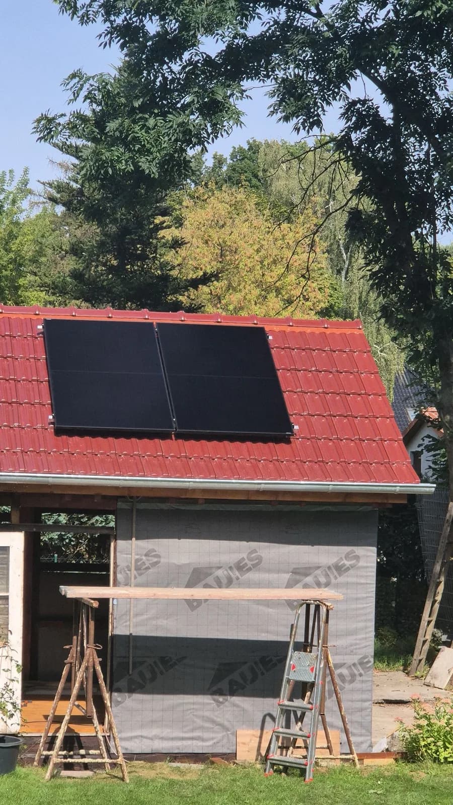 Gartenhaus mit zwei Solarmodulen auf rotem Dach